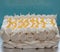 Large piped meringue pavlova cake, decorated with piped cream and lemon curd in a herringbone pattern.