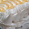 Large piped meringue pavlova cake, decorated with piped cream and lemon curd in a herringbone pattern.