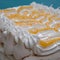 Large piped meringue pavlova cake, decorated with piped cream and lemon curd in a herringbone pattern.