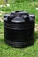 A large plastic black barrel for a summer shower. A container for storing water, food and fuel