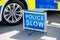 Large Police Slow sign on the road beside a patrol vehicle.