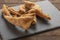 Large pork rinds on slate dish and wooden table
