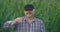 A large portrait of a farmer looking into the camera at dawn in the morning taking off his cap in a field with corn