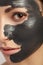 It is large portrait of girl with black clay mask.