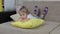 A large portrait of a little girl lying on a sofa leaning on a yellow pillow moving her legs