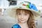 Large portrait of a lovely blue-eyed teenage girl in a straw hat with flowers. A charming girl with long fluffy hair looks at the