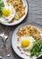 Large potato latkes, fried egg, arugula - tasty breakfast or snack on a gray background