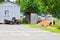 A large professional agricultural lawn mower, a lawn mowing tractor with grass, stands near the tool shed