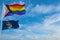 large progress lgbtq flag and flag of Maine state, USA waving in the wind at cloudy sky. Freedom and love concept. Pride month.