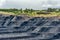 A large quarry with many horizons and ledges. Vertical bedding of coal seams.