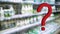 Large red 3d question mark on abstract blur supermarket background. Defocused shelves with food and dairy products. Grocery Store