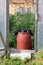 A large red barrel of water stands in the door of the wooden greenhouse