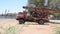 A large red old antique broken down water machine truck parked in the sand by trees in the United Arab Emirates