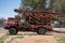 A large red old antique broken down water machine truck parked in the sand by trees in the United Arab Emirates