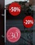 Large red sales poster at the entrance to a retail sale of clothing. Discount labels at the entrance to the store. Sale up to 50