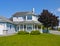 Large residential house with surrounding porch and big green lawn at the entrance