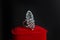 A large ring with small gems on a red box on a dark background. Women`s jewelry