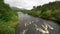 A large river that flows between green meadows and tall trees in the Glencoe Valley, Scotland.