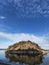 Large rock island in the sea or a lake in Finland. It is fully rock and has coniferous trees like pine trees and some bushes. The