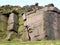 Large rock outcrop boulders with a stone wall along the top in yorkshire moorland