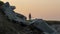 Large rocks on the coast with the Point Junith Lighthouse and an orange sky at dawn