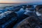 Large rocks covered with ice are flooded with sea water during dawn.