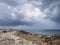 Large rocks on the shores of the Mediterranean Sea, dramatic skies and rain over the largest sailing yacht in the world, an eight-