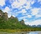 A large rocky mountain behind a green lake below.