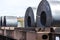 Large rolls of sheet metal lying on a freight wagon pulled by locomotives.