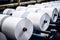 Large rolls of white paper sit on a machine in a factory, ready to be processed.