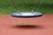 Large rubber swing with elastic middle suspended in air with four strong chains over playground sand in local park surrounded with