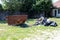 Large rusted old open empty trash dumpster with pile of garbage in open and ripped black plastic bags next to it