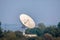 Large satellite dish on the forest over clouded background