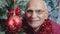 Large scale portrait of older man face looking with smile near Christmas tree.