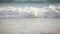 Large sea wave crashing sandy beach shore, telephoto close-up