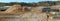 Large sewer pipes and heaps of sand with traces of heavy equipment wheels on a construction site in the forest.