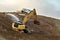 Large shovel excavator on the side of a hill with a man spraying water