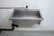 Large silver metal washing sink and piping inside a common use laundry room inside shot front view