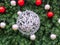 A large silver wicker ball entwined with a garland hangs in the center in the fir branches with small red and silver