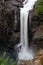 A large single drop waterfall cascading into the river below