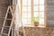 Large skylights with wooden trim, curtains and stepladder. Beautiful morning. Zamioculcas House plant in a straw pot stands on a w