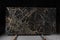 A large slab of dark expensive marble with yellow streaks stands on the counter, called New Portoro