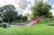 A large slide on a small hill and several swings at the entrance to Duthie park near Dee river, Aberdeen