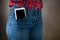 A large smartphone sticks out of a pocket tight-fitting girls jeans