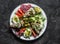 Large snack, appetizers, tapas plate - salami, mackerel cream cheese sandwiches, olives, avocado, tomatoes on a dark background,