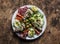 Large snack plate - salami, mackerel cream cheese sandwiches, olives, avocado, tomatoes on a wooden background, top view