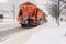 A large snowplow removes snow from the road