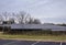 Large solar panel array in an overgrown field behind a chain link protective fence