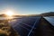 Large solar power plant with rows of photovoltaic panels neatly arranged against a clear blue sky. Representing the harmonious