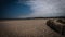 Large space on the beach, rustic wooden fence, wild vegetation, blue sky, clouds